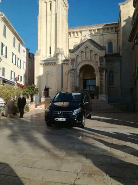 Corbillard noir Mercedes stationné sur le parvis d'une église.