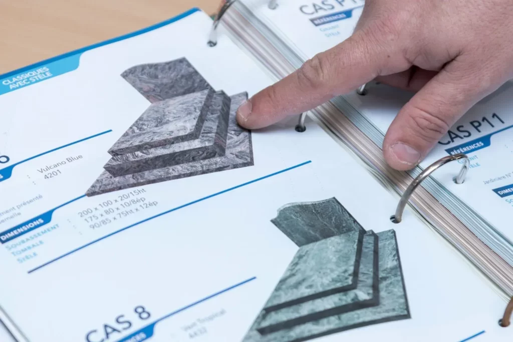 Consultation d'un catalogue de monuments et stèles funéraires en marbre.