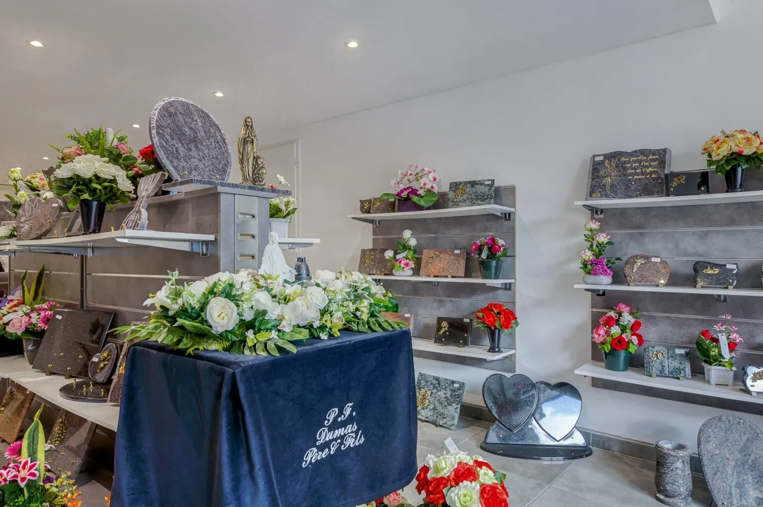 Magasin d'articles funéraires présentant fleurs artificielles et plaques en granit.