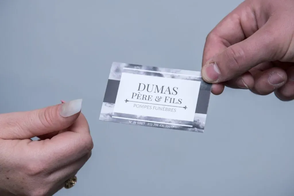 Échange d'une carte de visite professionnelle des Pompes Funèbres Dumas.
