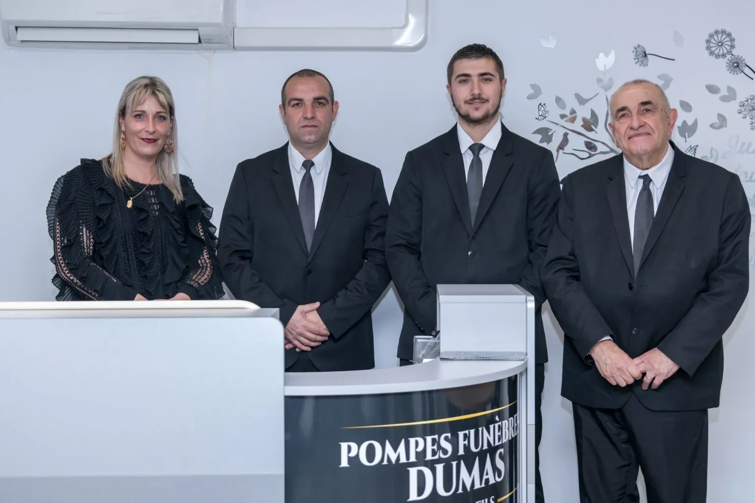 Équipe des Pompes Funèbres Dumas réunie autour du comptoir d'accueil de l'agence.